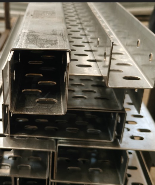 Close-up view of aluminum perforated cable trays showing slots and channel design for cable management.